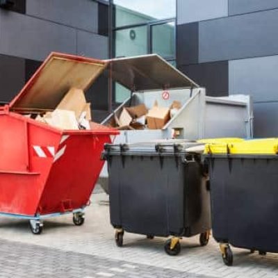 Red dumpster, recycle waste and garbage bins near new office building